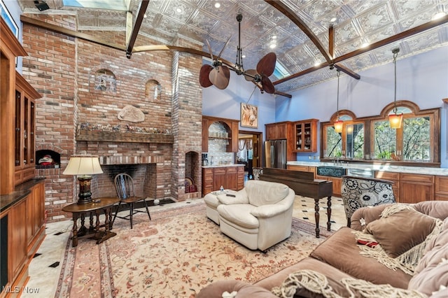 living room featuring beamed ceiling, high vaulted ceiling, a fireplace, and sink