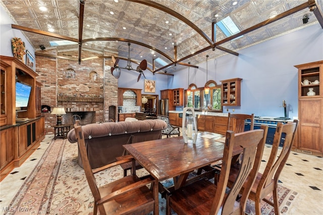 dining space featuring a fireplace, high vaulted ceiling, and a skylight