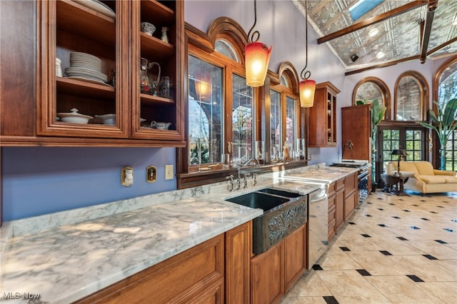 kitchen with light stone counters, stainless steel appliances, decorative light fixtures, lofted ceiling, and light tile patterned flooring