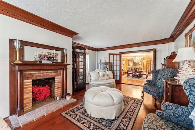 living room with a textured ceiling, hardwood / wood-style flooring, a brick fireplace, and crown molding