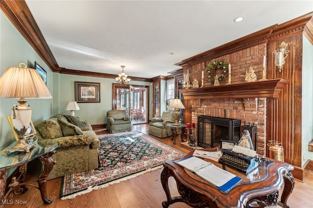 living room with a fireplace, light wood-type flooring, crown molding, and a notable chandelier