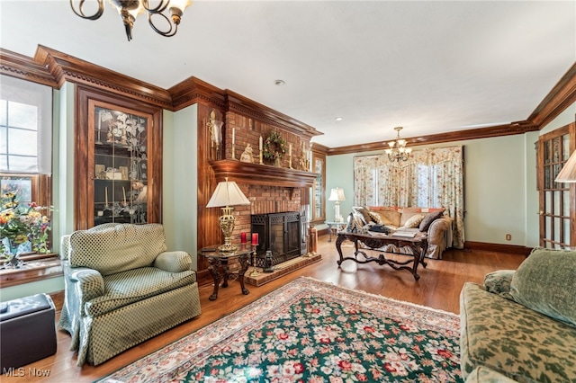 living room with ornamental molding, a fireplace, light hardwood / wood-style floors, and an inviting chandelier