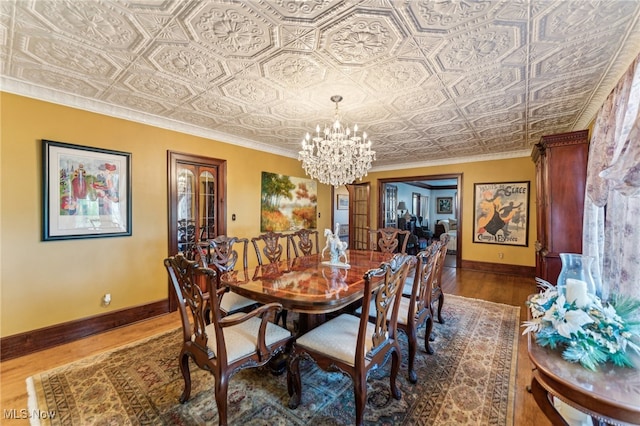 dining space with dark hardwood / wood-style flooring, an inviting chandelier, and ornamental molding