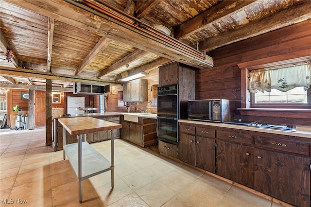 kitchen featuring wooden counters, wood ceiling, dark brown cabinetry, wooden walls, and black appliances