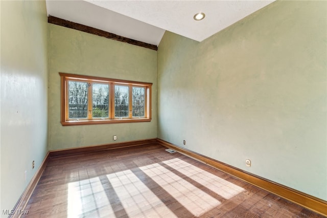 empty room featuring hardwood / wood-style floors and vaulted ceiling