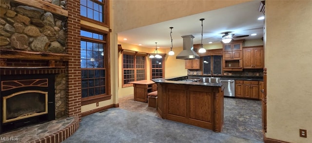 kitchen featuring island exhaust hood, backsplash, stainless steel dishwasher, a large fireplace, and hanging light fixtures