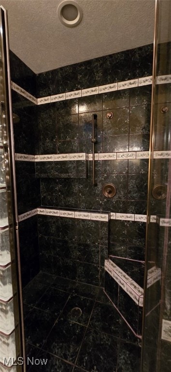 bathroom featuring a tile shower and a textured ceiling