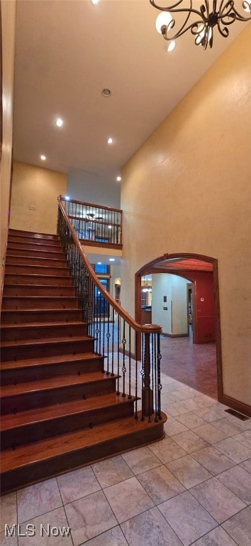 stairway featuring a high ceiling and a chandelier