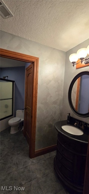 bathroom with tile patterned floors, vanity, a textured ceiling, and toilet