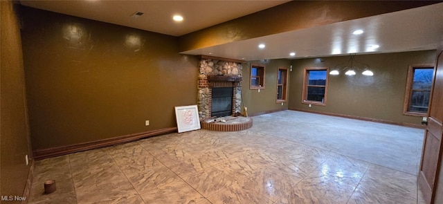 unfurnished living room with a chandelier and a stone fireplace