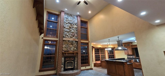 kitchen with carpet, island range hood, a high ceiling, a kitchen island, and hanging light fixtures