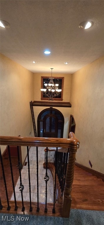 stairway with a chandelier and hardwood / wood-style flooring