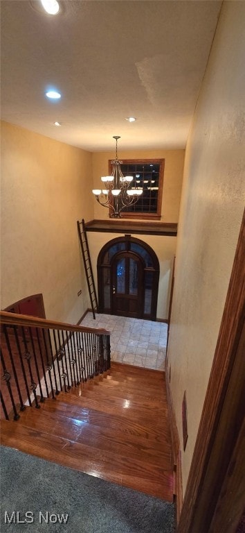 staircase with a chandelier and hardwood / wood-style floors