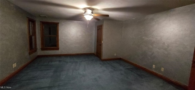 empty room featuring ceiling fan and dark carpet