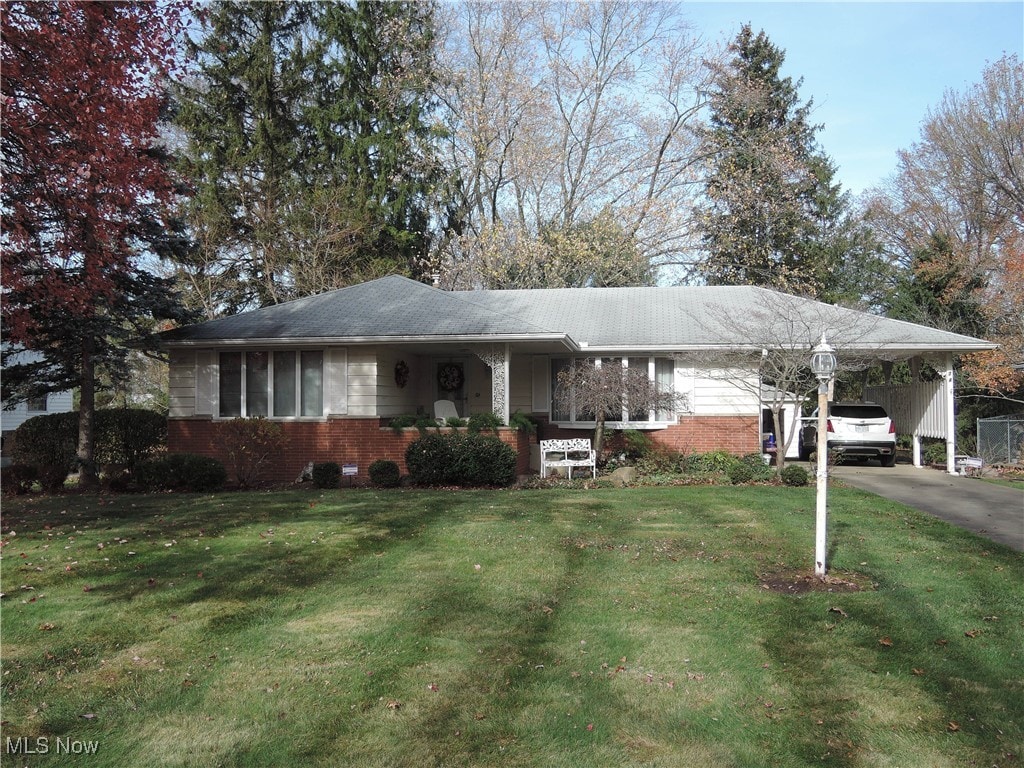 ranch-style home featuring a front lawn and a carport