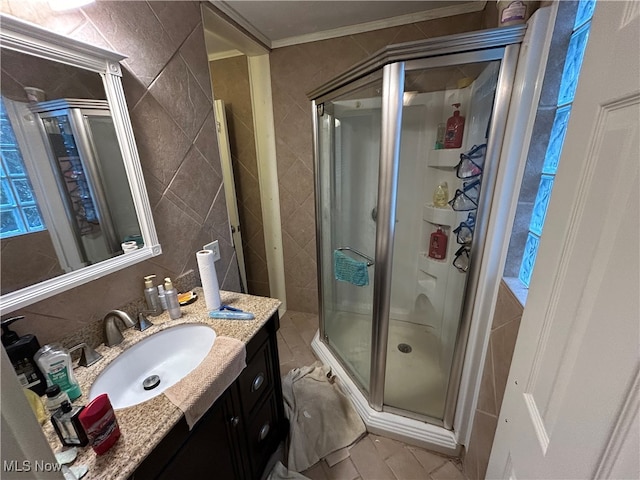 bathroom featuring a shower with shower door, ornamental molding, tile walls, and vanity