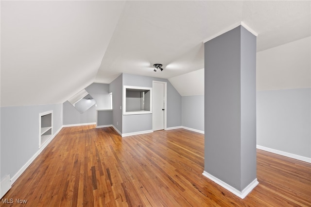 additional living space featuring built in shelves, hardwood / wood-style floors, and lofted ceiling