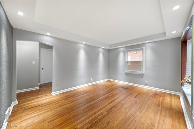 unfurnished room featuring a tray ceiling and light hardwood / wood-style flooring