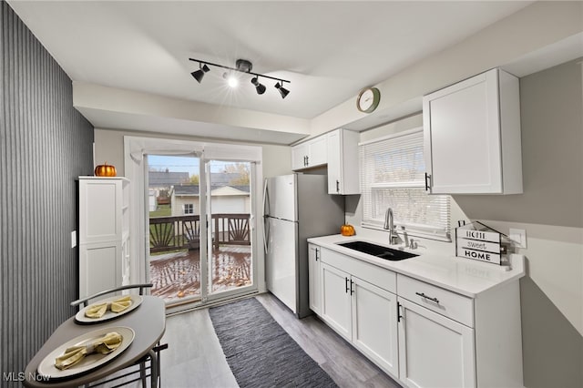 kitchen with white cabinets, light wood-type flooring, and sink