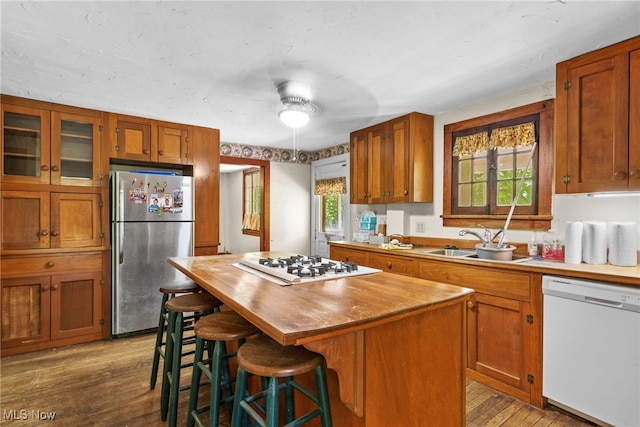 kitchen with a kitchen breakfast bar, white appliances, ceiling fan, a center island, and light hardwood / wood-style floors