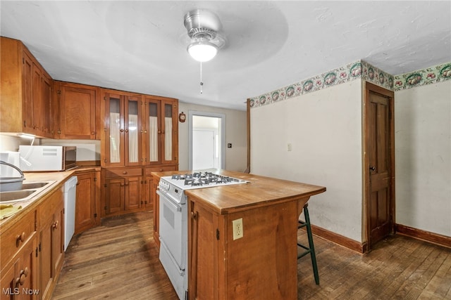 kitchen featuring white appliances, a kitchen island, ceiling fan, and dark wood-type flooring