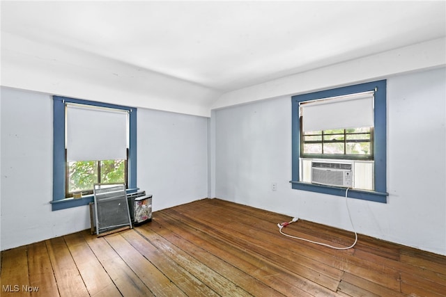 unfurnished room featuring hardwood / wood-style flooring, vaulted ceiling, and cooling unit