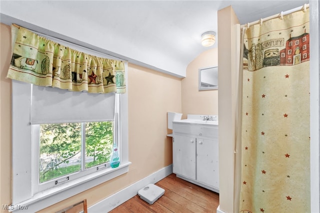 bathroom with hardwood / wood-style floors, vanity, and lofted ceiling