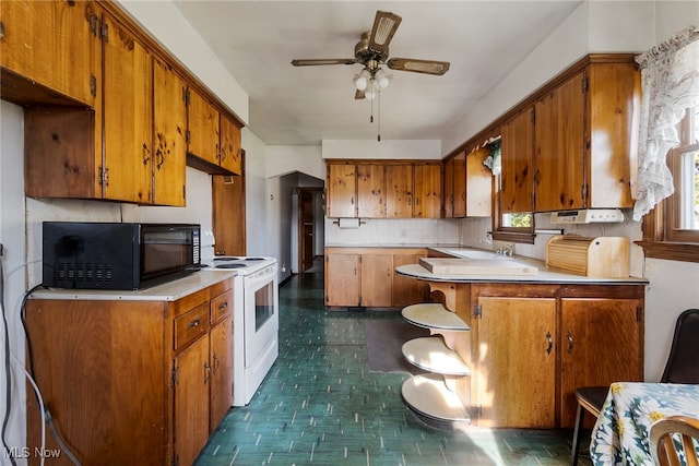 kitchen with kitchen peninsula, ceiling fan, and white range