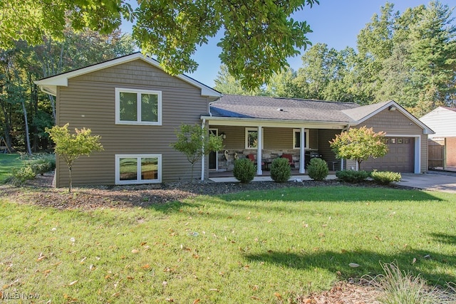 tri-level home with covered porch, a garage, and a front yard