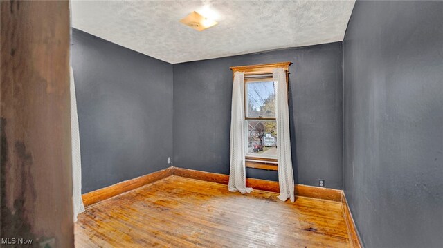 spare room featuring hardwood / wood-style flooring and a textured ceiling