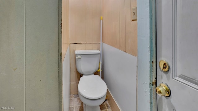 bathroom with wood walls and toilet