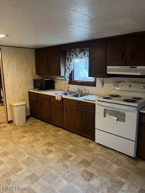 kitchen featuring dark brown cabinets, white range with electric stovetop, wooden walls, and exhaust hood