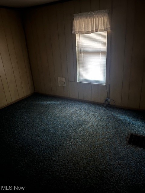 carpeted spare room with wooden walls