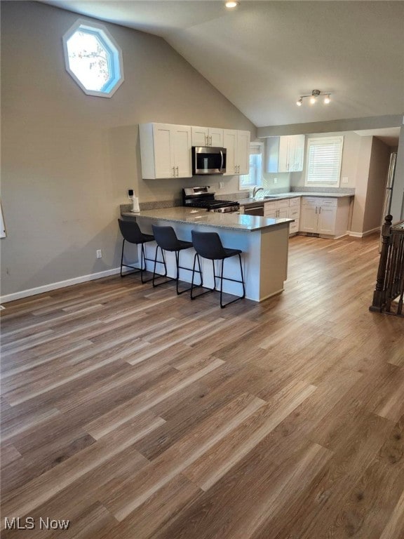 kitchen with a wealth of natural light, white cabinetry, kitchen peninsula, and appliances with stainless steel finishes