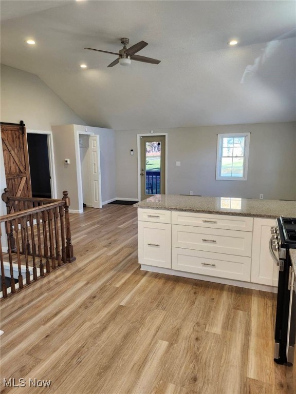 kitchen with a barn door, light wood-type flooring, and white cabinetry