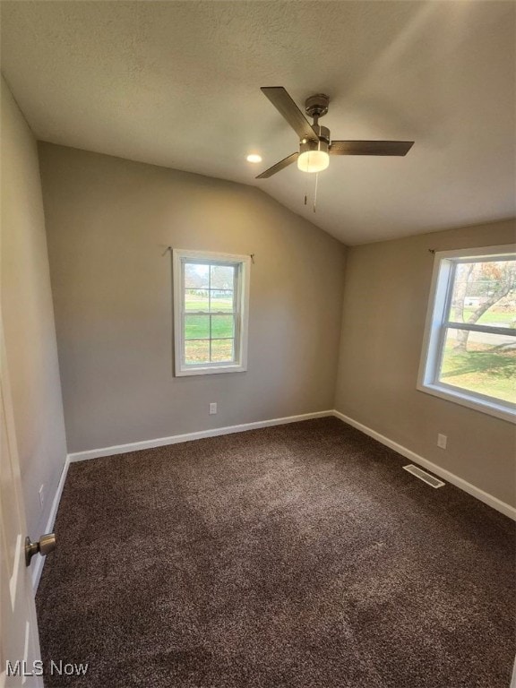 carpeted spare room with a textured ceiling, vaulted ceiling, and ceiling fan