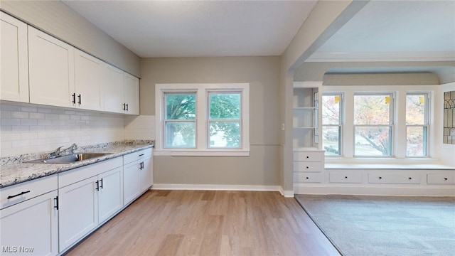 kitchen with plenty of natural light, light hardwood / wood-style floors, white cabinetry, and sink