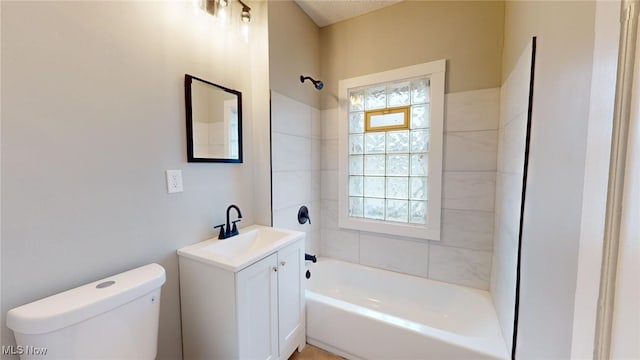 full bathroom featuring vanity, tiled shower / bath combo, and toilet