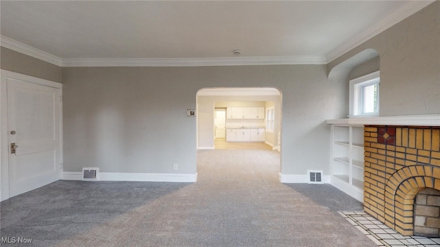 unfurnished living room featuring carpet, crown molding, and a brick fireplace