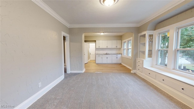 unfurnished living room with light carpet, plenty of natural light, and crown molding