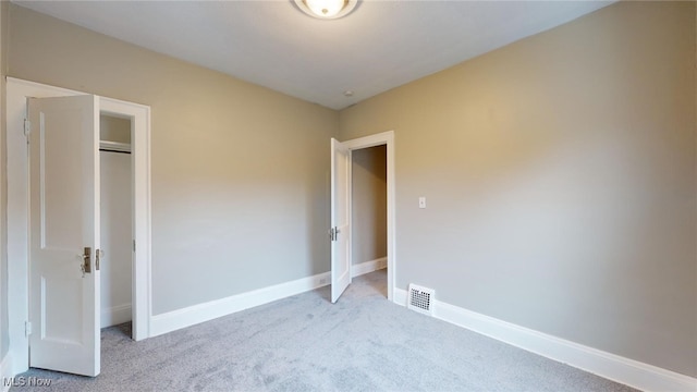 unfurnished bedroom with light carpet and a closet