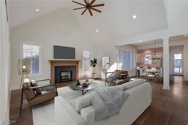 living room with dark hardwood / wood-style floors, ceiling fan with notable chandelier, and high vaulted ceiling