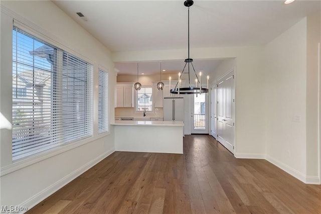 kitchen with hanging light fixtures, a notable chandelier, white cabinetry, dark hardwood / wood-style flooring, and kitchen peninsula