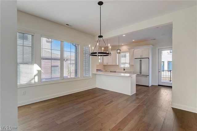 kitchen featuring kitchen peninsula, dark hardwood / wood-style flooring, high end white refrigerator, white cabinetry, and hanging light fixtures