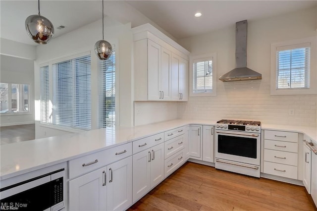 kitchen with wall chimney exhaust hood, high end white range oven, stainless steel microwave, and a wealth of natural light