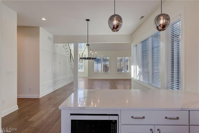 kitchen featuring light stone countertops, white cabinetry, dark wood-type flooring, wine cooler, and pendant lighting