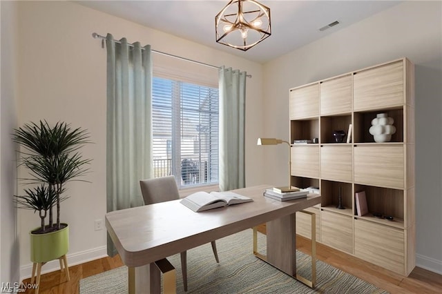 office with hardwood / wood-style floors and a notable chandelier