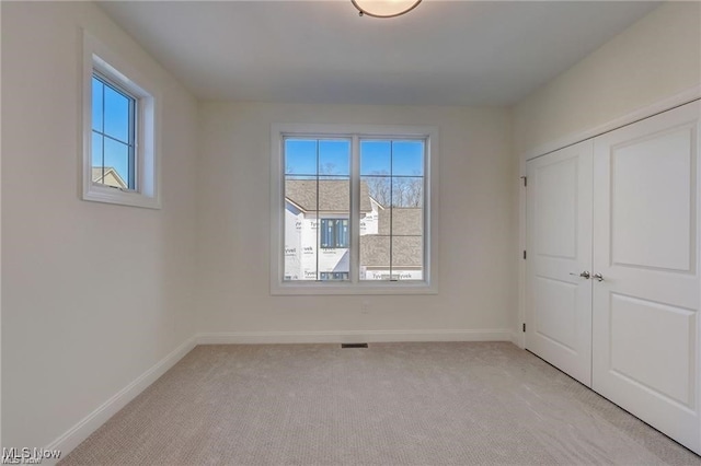 unfurnished bedroom featuring light colored carpet and a closet