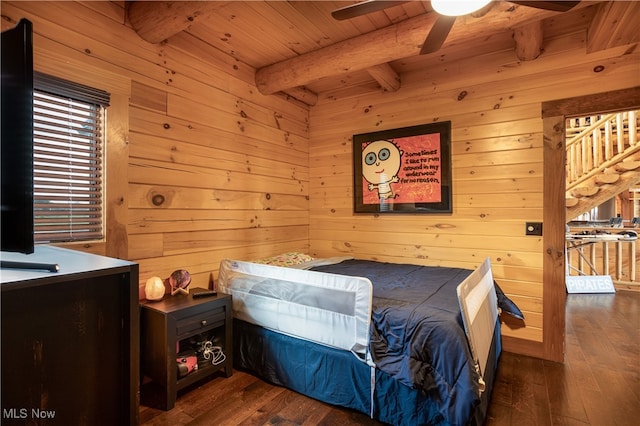 bedroom with beam ceiling, wooden walls, and dark wood-type flooring