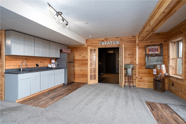 kitchen with stainless steel fridge, carpet floors, sink, and wooden walls